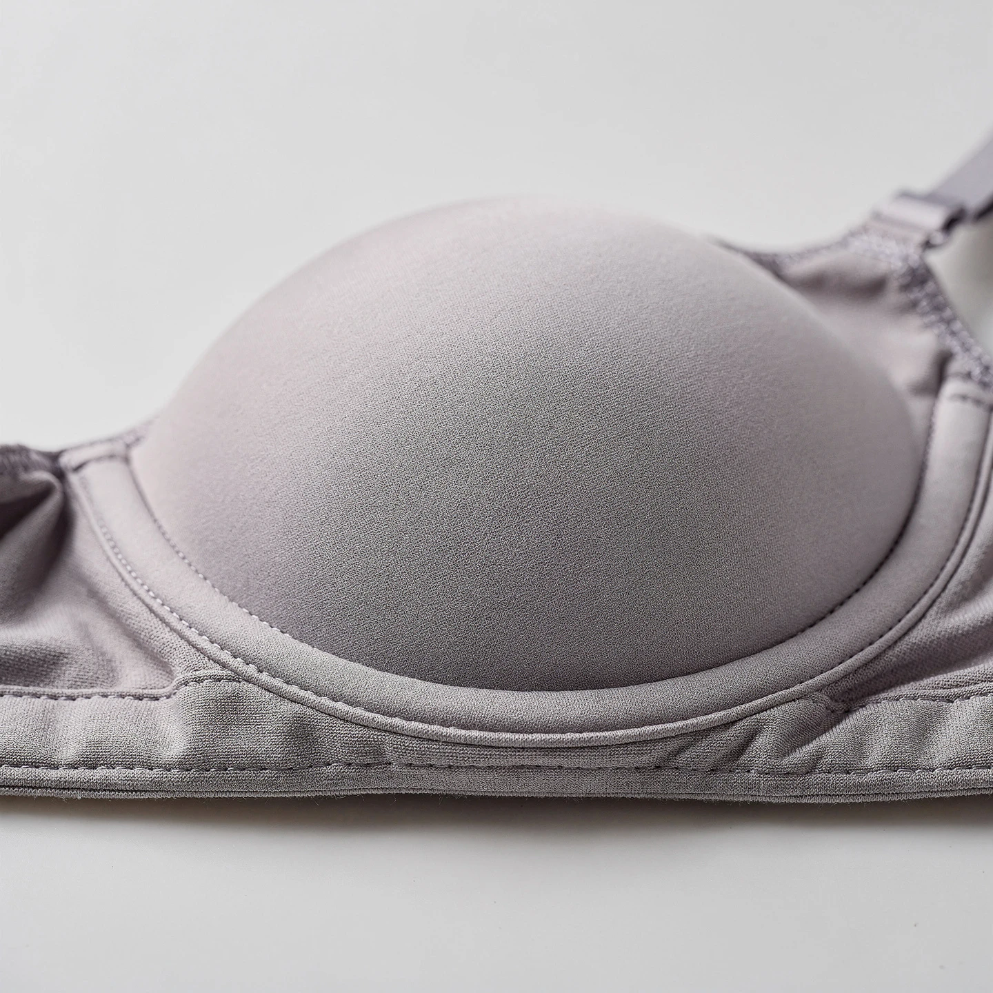 Biustonosz z watowanymi miseczkami formowanymi termicznie leżący na jasnym tle, widok z boku podkreślający grubość miseczki i jej wypukły kształt